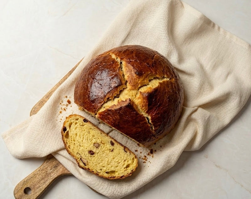 Velikonoční mazanec s hladkým povrchem a naříznutým křížkem na pečicím papíru